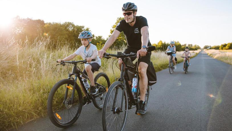 Fietsend gezin op een lange, rechte landweg op Kær Halvø