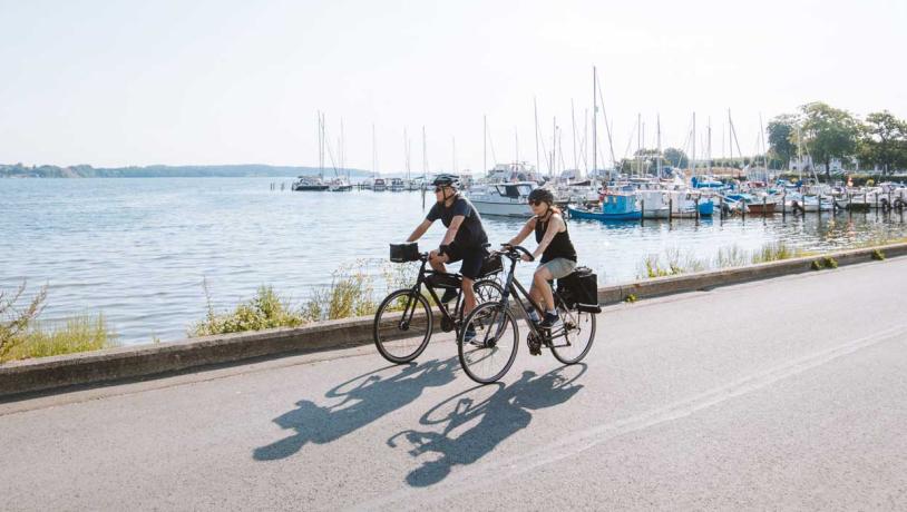 Pärchen fährt Fahrrad am Yachthafen von Kalvø
