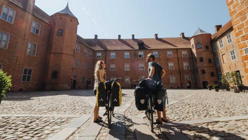 Paar met fietsen op de binnenplaats van het Kasteel van Sønderborg