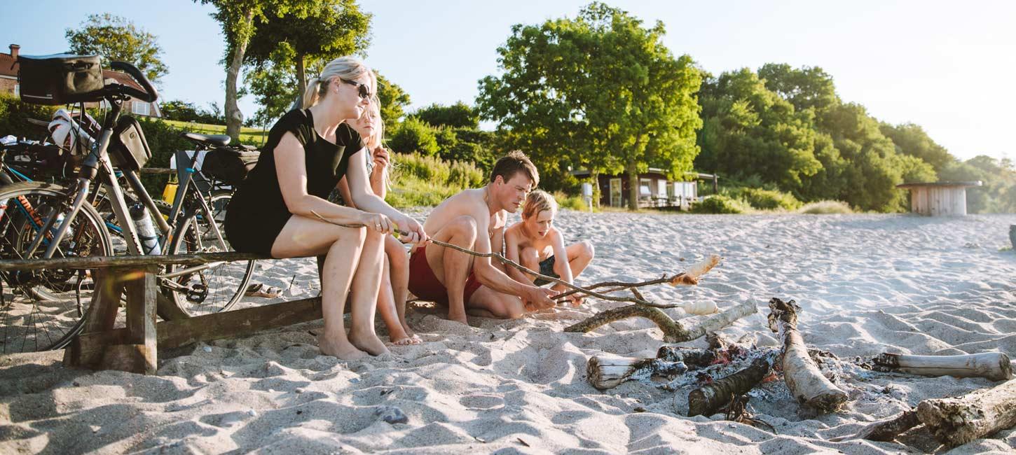 Gezin met fietsen bij een kampvuur op het strand