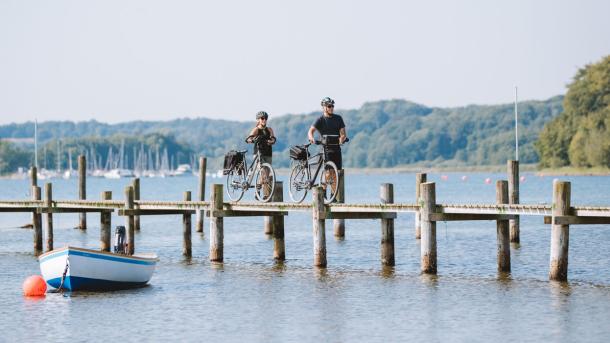 Ein Pärchen mit Fahrrädern auf der Brücke am Genner Strand