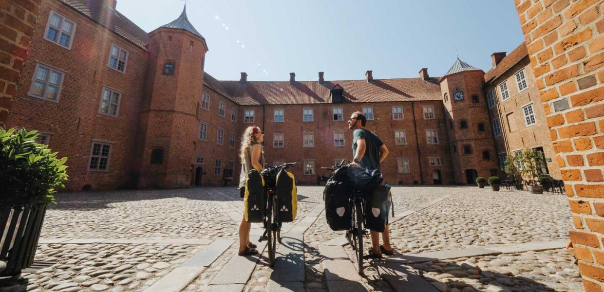 Paar met fietsen op de binnenplaats van het Kasteel van Sønderborg