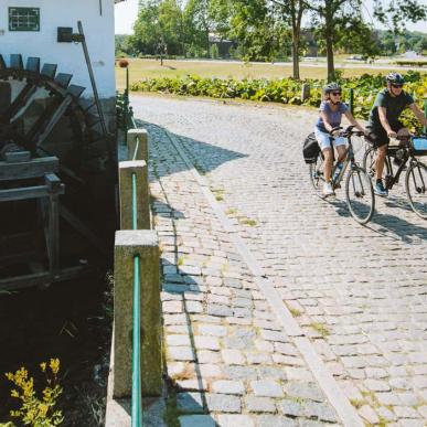 Pärchen fährt Fahrrad an der alten Schlossmühle in Aabenraa