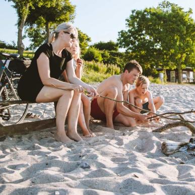 Familie på stranden med cykler og bål