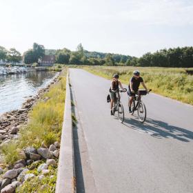 Ein Pärchen fährt Fahrrad über dem Damm von Kalvø
