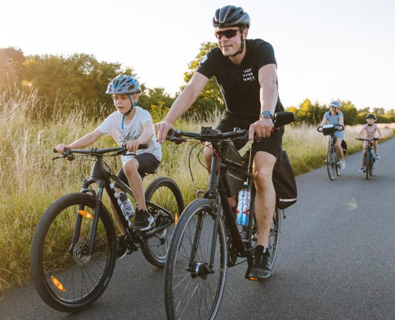 Fietsend gezin op een lange, rechte landweg op Kær Halvø