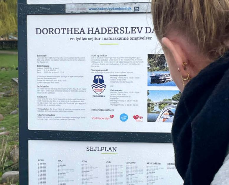 Dame står og kigger på sejlplan for dambåden i Haderslev 
